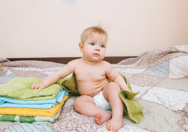 Cute baby 6 mesi seduto accanto a una pila di asciugamani