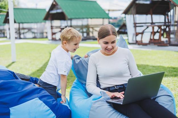 Cute giovane madre e figlio guardando il computer portatile Famiglia felice madre e figlio stanno riposando nel parco Una donna in congedo di maternità