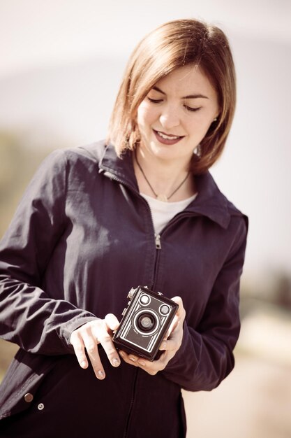 Cute girl is making pictures with a vintage camera outside