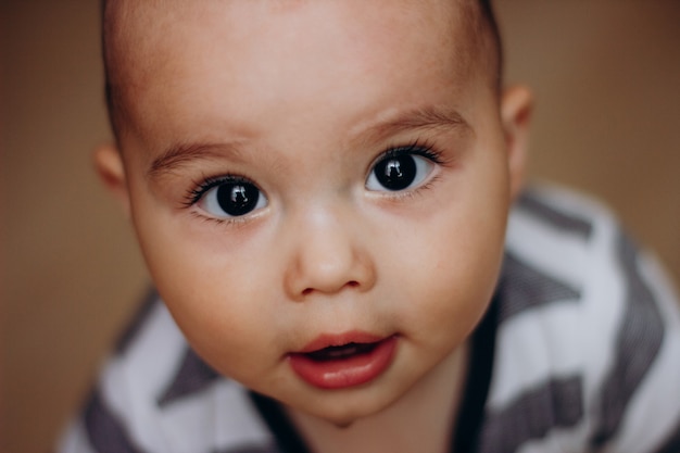 Cute little baby boy con grandi occhi scuri e lunghe ciglia. Ritratto di dolce neonato