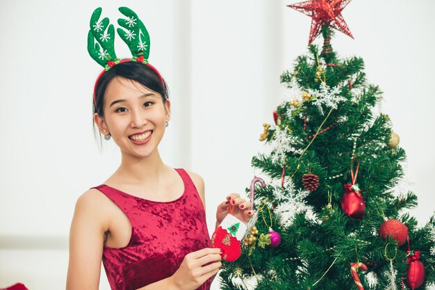 Cute ragazza asiatica adolescente decorare l'albero di Natale per il sorriso felice di evento di festa di Capodanno