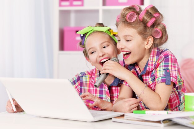 Cute tweenie girls in bigodini con laptop, cantando al karaoke a casa