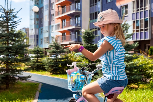 Da dietro del bambino in estate cappello in bicicletta all'aperto nel parco cittadino e girato mostrando il dito lontano