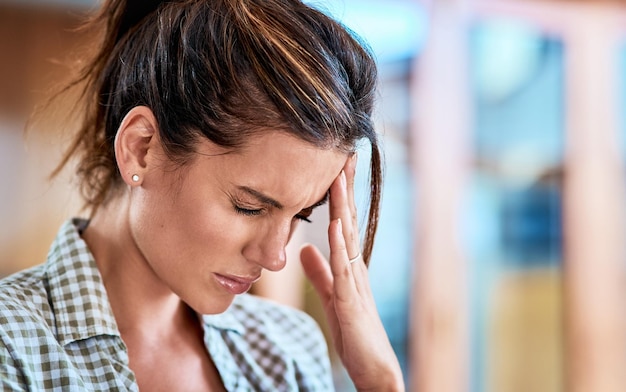 Da dove viene questo mal di testa all'improvviso Inquadratura di una donna dall'aspetto a disagio che si tiene la testa a disagio a causa del dolore a casa durante il giorno