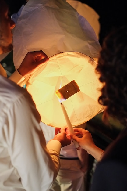 Dà fuoco a una lanterna di carta celeste prima di lanciarsi nel cielo buio della sera