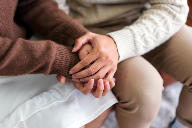 Da vicino donna e uomo innamorati seduti sul divano due persone che si tengono per mano simbolo di sentimenti sinceri