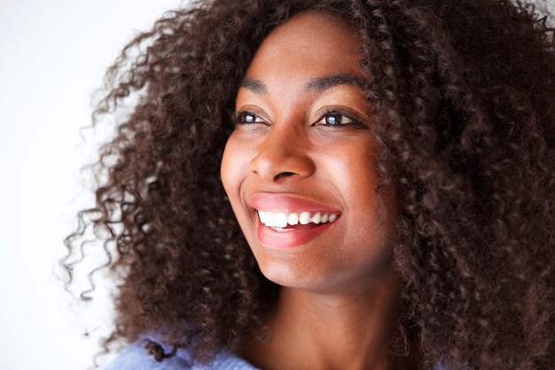 Da vicino una bella giovane donna africana con i capelli ricci che guarda lontano sorridendo