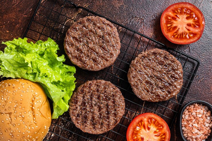Photo daging hamburger panggang dengan tomat dan bumbu di atas meja dapur latar belakang gelap tampilan atas