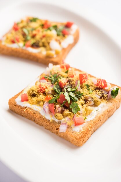 Dahi Bread papdi chaat, chat è un gustoso antipasto o antipasto indiano, servito in un piatto guarnito con pomodoro, sev e coriandolo e masala. messa a fuoco selettiva