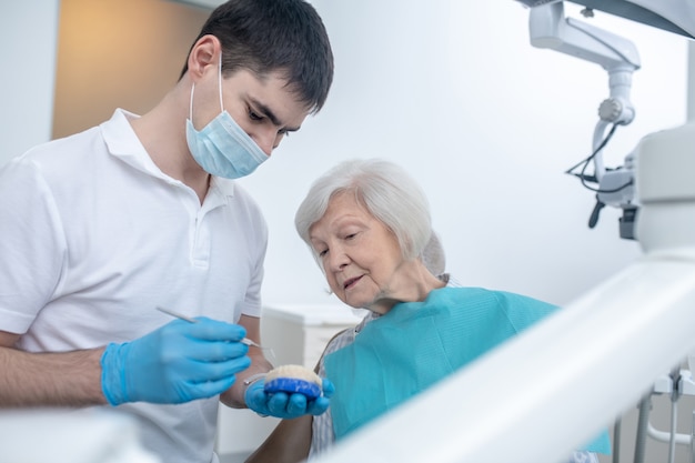 Dai dentisti. Dentista maschio che parla con la sua paziente senipr e spiega la sua diagnosi