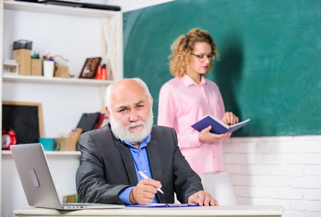 Dai un'occhiata al corso a scuola studente e tutor con laptop che risponde studente ragazza con tutor uomo alla lavagna insegnante senior e donna a scuola lezione supera l'esame stanza degli insegnanti