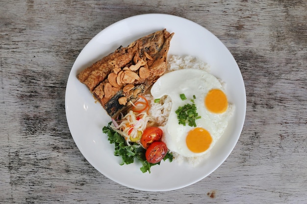 Daing Na Bangus con uova soleggiate e riso con pomodoro con insalata servita in un piatto isolato su sfondo di legno vista dall'alto della colazione