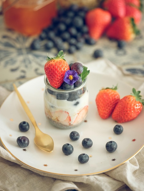 Dall'alto di gustoso yogurt con fragole fresche e mirtilli servito in un barattolo di vetro sul tavolo per la colazione