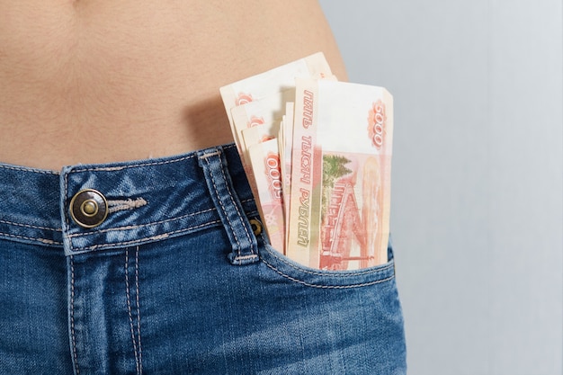 Dalla tasca anteriore dei jeans della ragazza spuntano 5 mila rubli russi. foto orizzontale