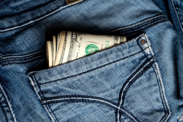 Dalla tasca posteriore dei vecchi jeans spuntano alcune banconote da un dollaro