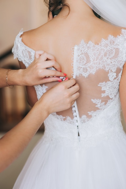 damigella d&#39;onore abbottonare il vestito sulla sposa, dettagli di abito da sposa bellissimo pizzo