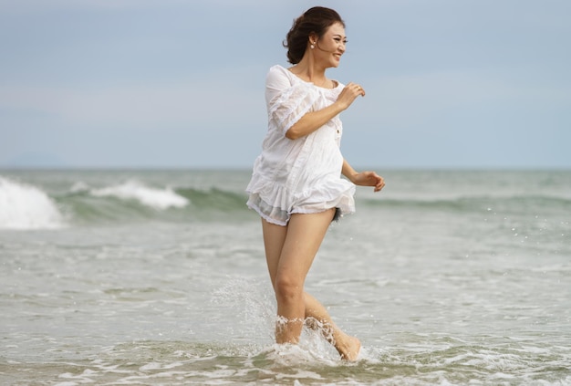 Danang, Vietnam - 20 febbraio 2016: Giovane ragazza che corre attraverso l'acqua in China Beach a Danang, Vietnam