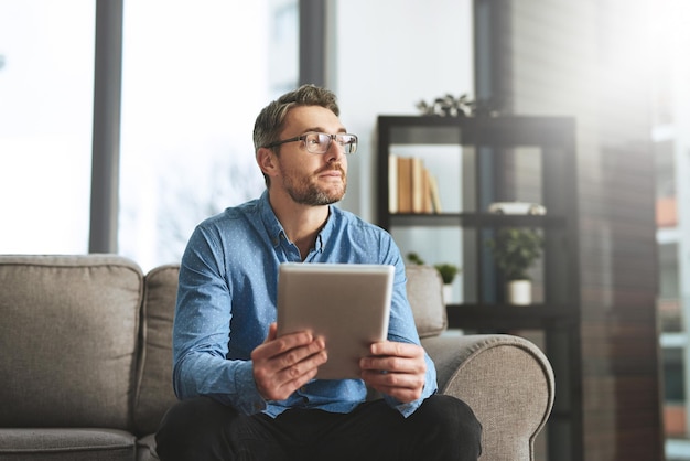 Dandoci qualche pensiero Scatto di un uomo d'affari che usa la sua tavoletta digitale mentre è seduto su un divano in ufficio