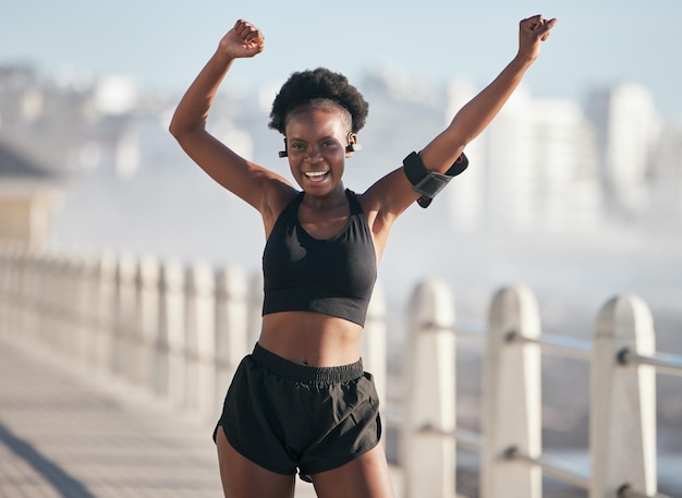 Danza fitness e ritratto di donna sulla spiaggia della città per l'esercizio energetico e la salute cardiovascolare con la tecnologia musicale Ascolto dell'allenamento e celebrazione della vittoria o del sì degli obiettivi della persona africana o del corridore