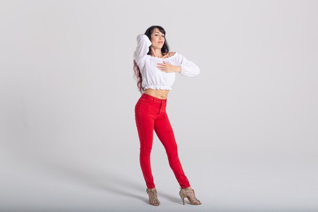 Danza latina, improvvisazione, concetto di danza contemporanea e di moda - giovane bella donna che balla su sfondo bianco studio con spazio copia