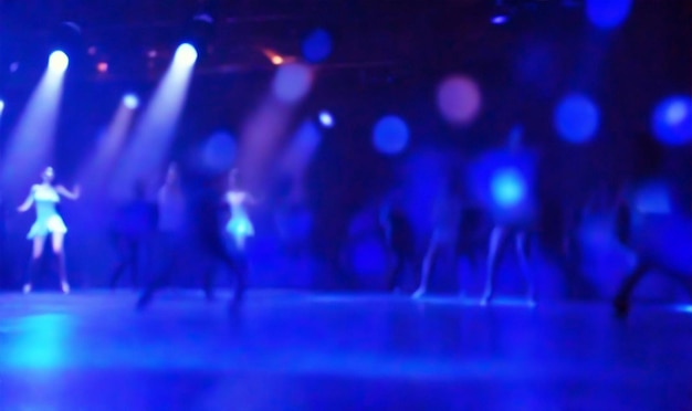 danza sfocata in una luce notturna del palco di un club su sfondo blu colorato