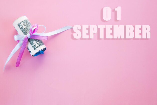 Data del calendario su sfondo rosa con banconote da un dollaro arrotolate appuntate da un nastro blu rosa 1 settembre