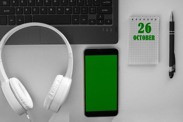 Data del calendario su uno sfondo chiaro di un desktop e un telefono con schermo verde Il 26 ottobre è il ventiseiesimo giorno del mese