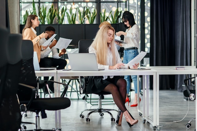 Dati entranti del giovane responsabile femminile abbastanza intenzionale dell'ufficio dal rapporto finanziario al computer portatile nell'ufficio moderno