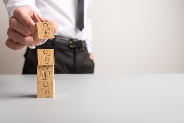 datore di lavoro di affari che impila i cubi di legno con il simbolo della gente su loro.