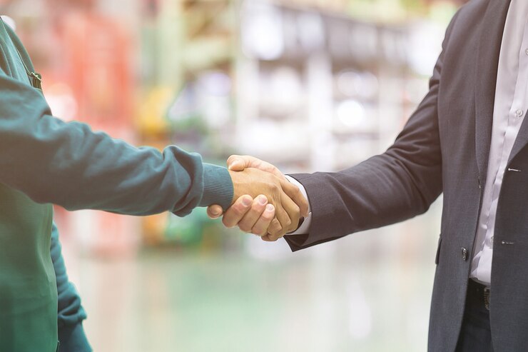 Datore di lavoro e lavoratore della stretta di mano di affari sul fondo vago del supermercato.