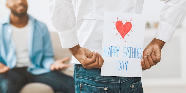 Daudghter saluta il padre con la ragazza che nasconde il biglietto di auguri per il giorno del padre