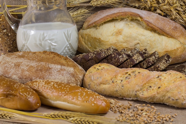 Decanter di latte. Diversi tipi di pane. Rametti d'avena.