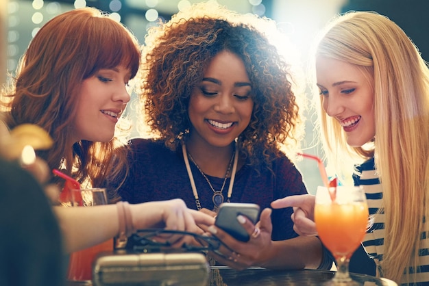 Decidere quale selfie condividere Inquadratura di un gruppo di amici felici che si godono un cocktail in una discoteca