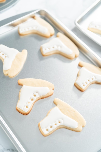 Decorare biscotti di zucchero a forma di pattini con ghiaccia reale.