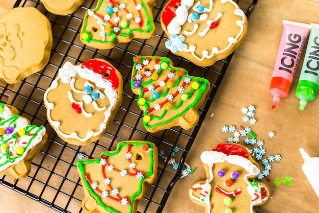 Decorare i biscotti di panpepato con ghiaccia reale e caramelle colorate.