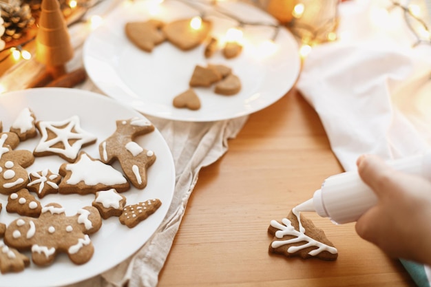 Decorare i biscotti di panpepato con glassa sulla tavola rustica Tradizione e avvento delle vacanze di Natale