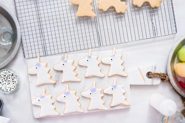 Decorare i biscotti di zucchero a tema unicorno con glassa reale.