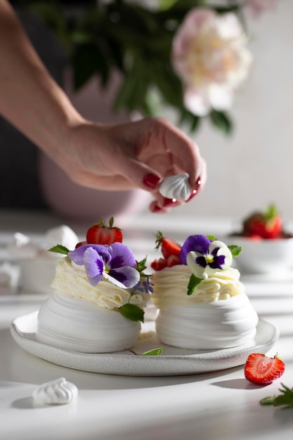 Decorare il dolce di Pavlova con fiori e frutti di bosco