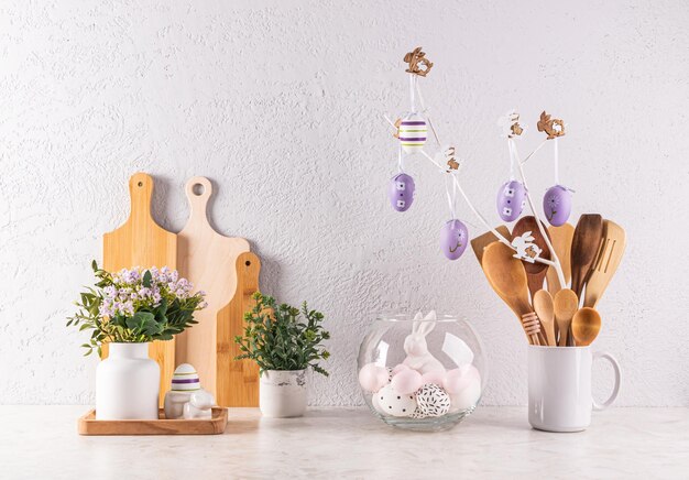 Decorare il piano della cucina per le vacanze di Pasqua Utensili da cucina in legno piante in vaso un ramo con uova lilla Vista frontale Stile ecologico