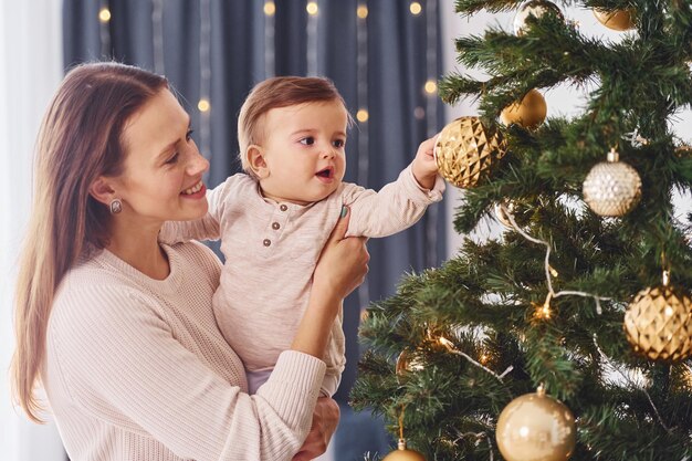 Decorare l'albero di Natale La madre con la sua piccola figlia è insieme in casa a casa