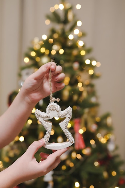 Decorare l'albero di natale tenendo il giocattolo di natale in una mano vacanza natale e capodanno famiglia cele...