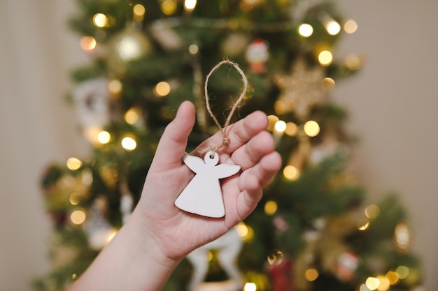 Decorare l'albero di natale tenendo il giocattolo di natale in una mano vacanza natale e capodanno famiglia cele...