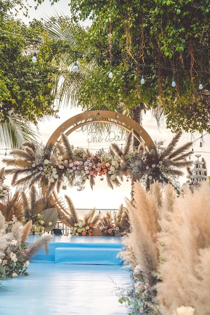 Decorare l'arco con fiori e stoffa per una cerimonia di matrimonio nella natura Cerimonia di matrimonio con fiori all'esterno in giardino con luci sospese