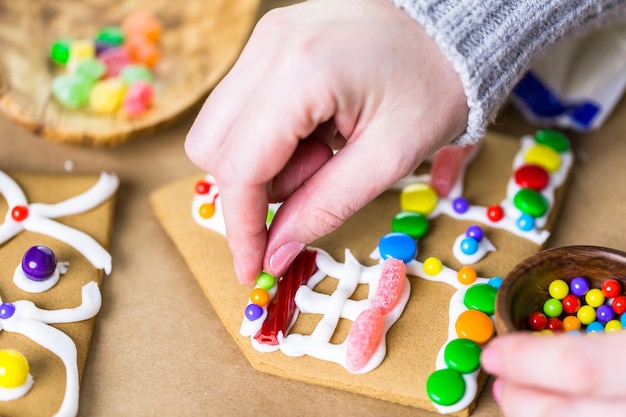 Decorare la casa di marzapane con ghiaccia reale e caramelle colorate.