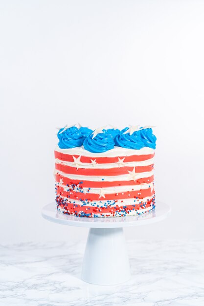 Decorare la torta al cioccolato con glassa al burro bianca, rossa e blu per la celebrazione del 4 luglio.
