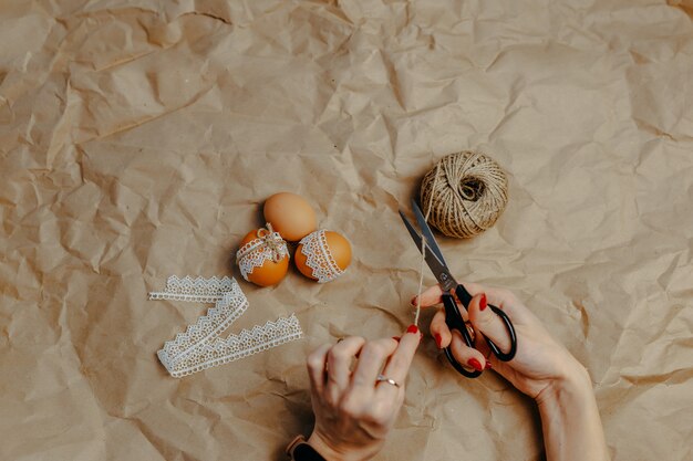 Decorare le uova di Pasqua su carta kraft con pizzo e corda