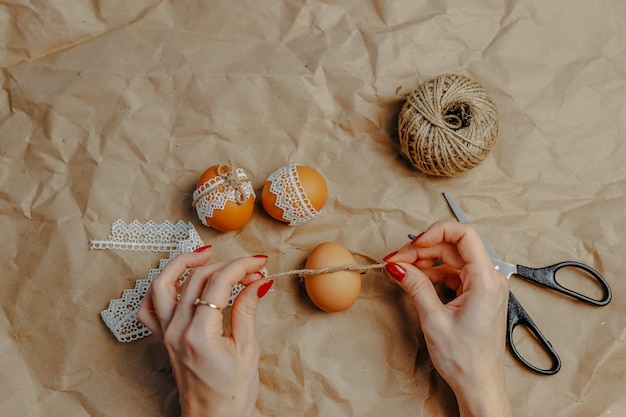 Decorare le uova di Pasqua su carta kraft con pizzo e corda