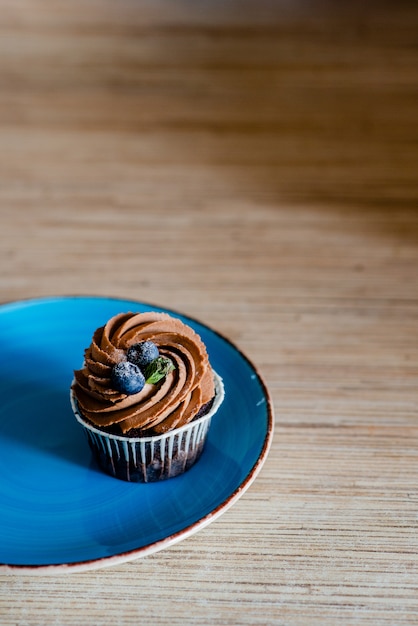 Decorato gustoso Cupcake con una fetta di fragola e cioccolato sul tavolo.