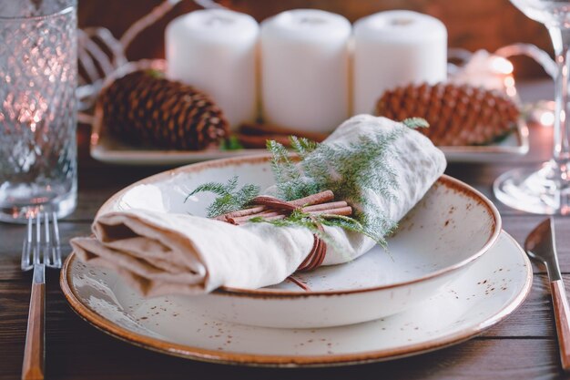 Decorato la tavola del Ringraziamento o del nuovo anno tra candele bianche e decorazioni invernali Il concetto di una cena festiva