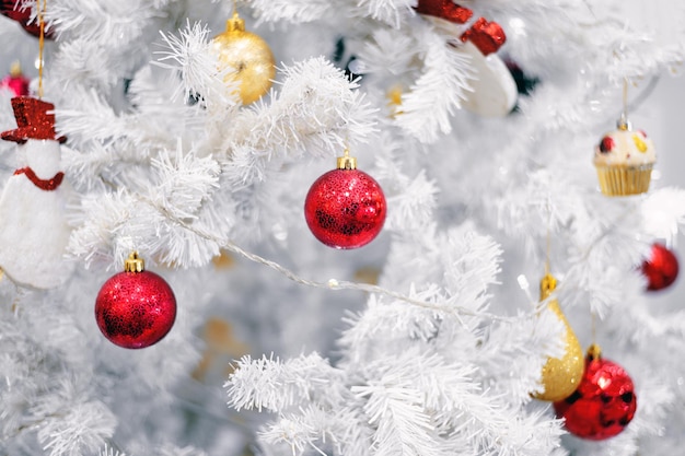 Decorazione bianca dell'albero di Natale con palline rosse su rami di abete